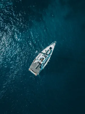 Un yate en mar abierto de azul profundo, visto desde arriba.
